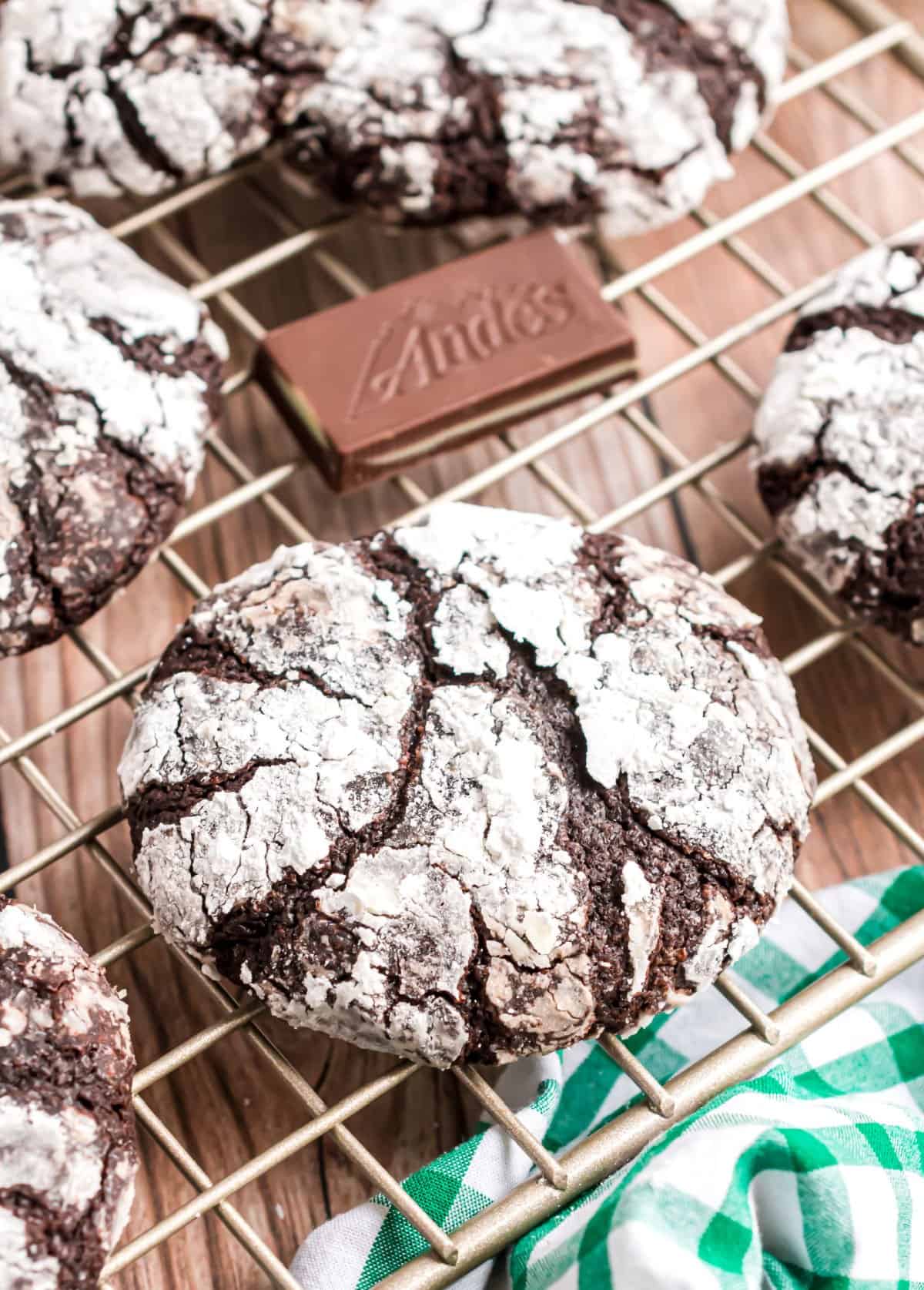 Chocolate crinkle cookie with andes mints on wire cooling rack.