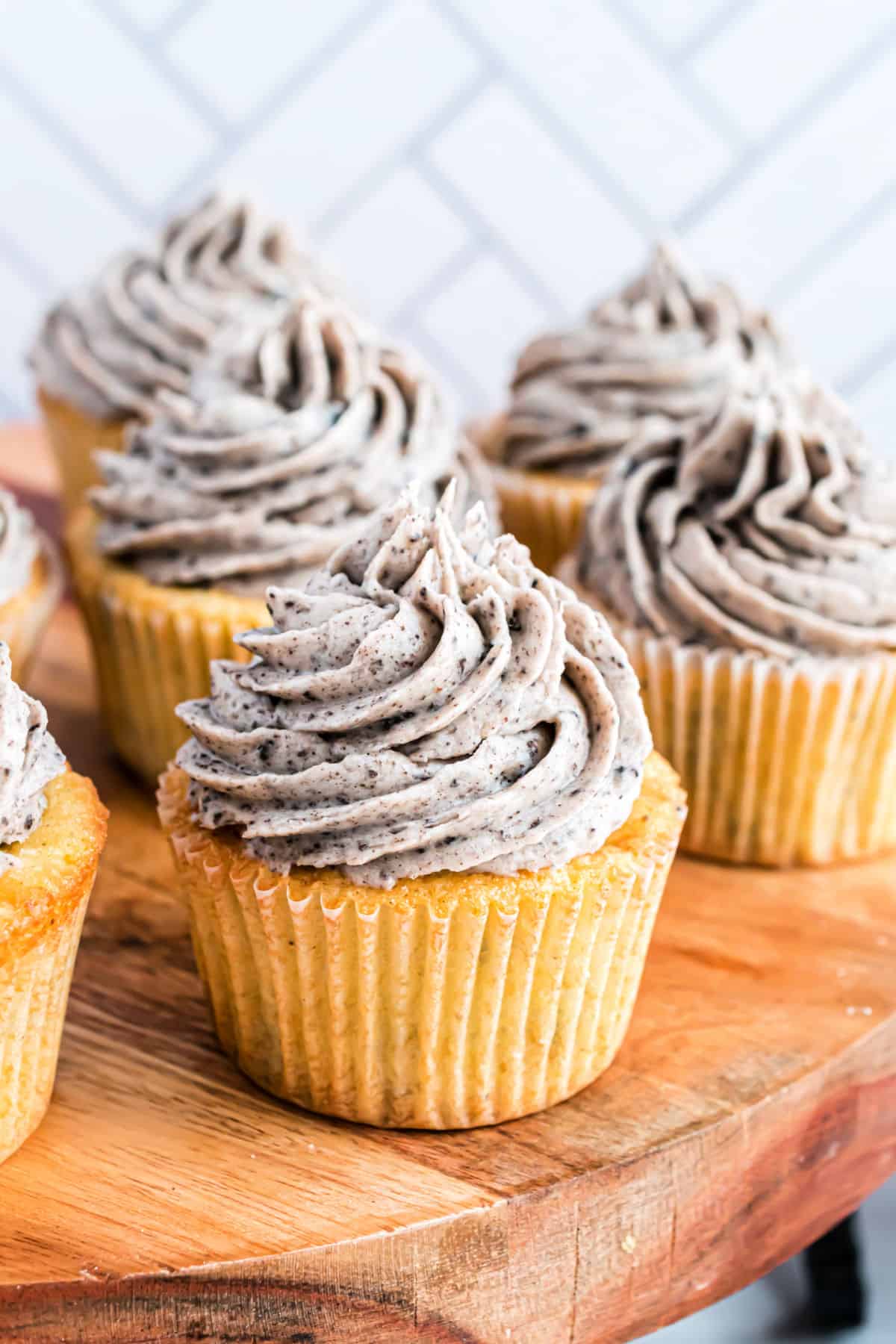 Oreo cupcakes with oreo frosting on a wooden cake platter.