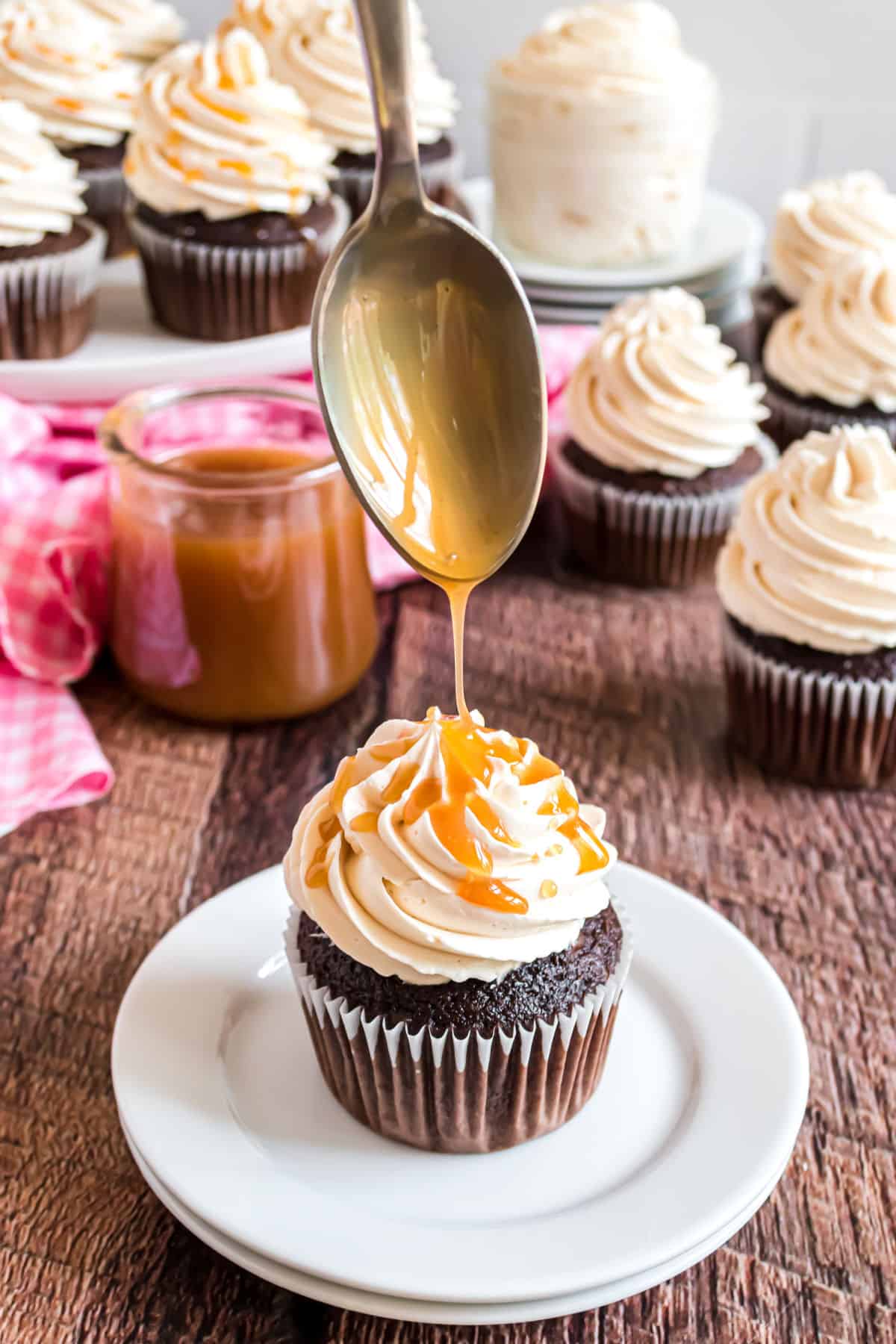 Caramel drizzled over the top of a swiss meringue frosted cupcake.