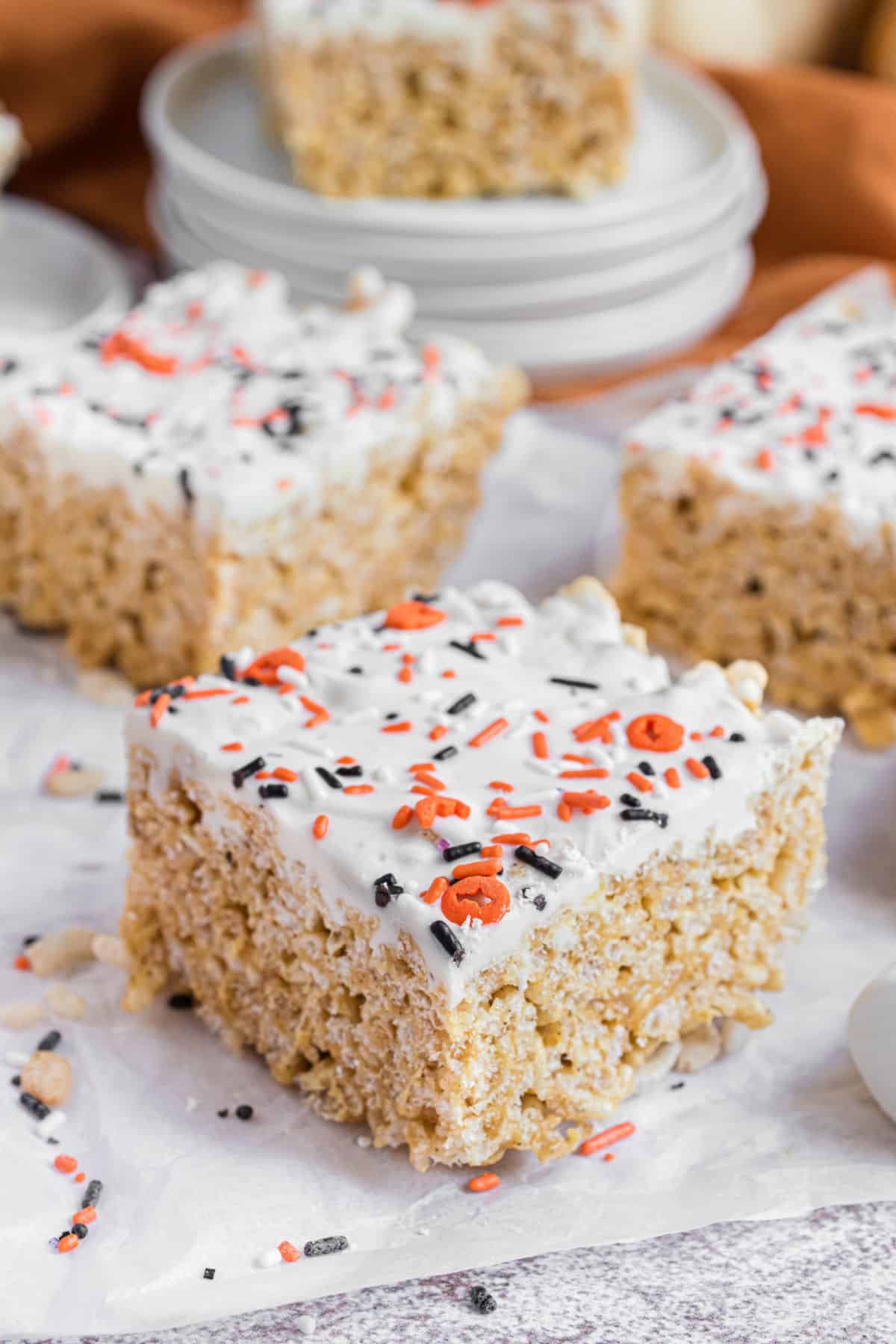 Pumpkin flavored rice krispie treats with white chocolate and sprinkles.