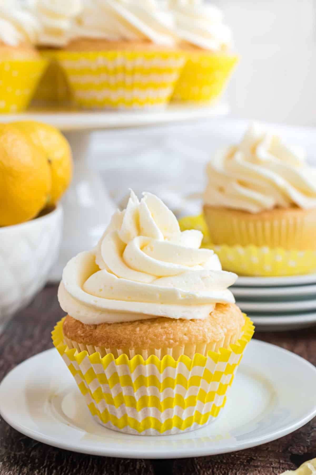 Lemon cupcake topped with lemon frosting on white plate.