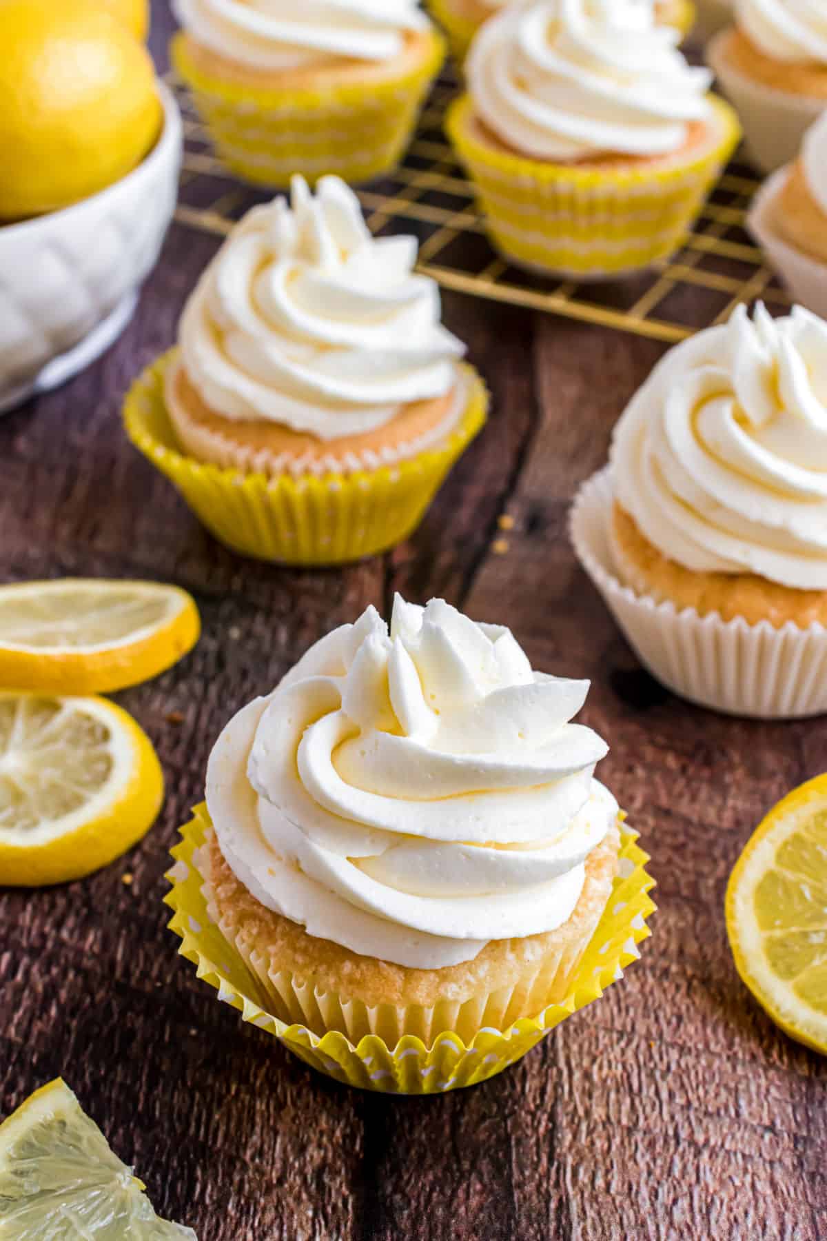 Lemon frosted cupcakes on a wooden board.