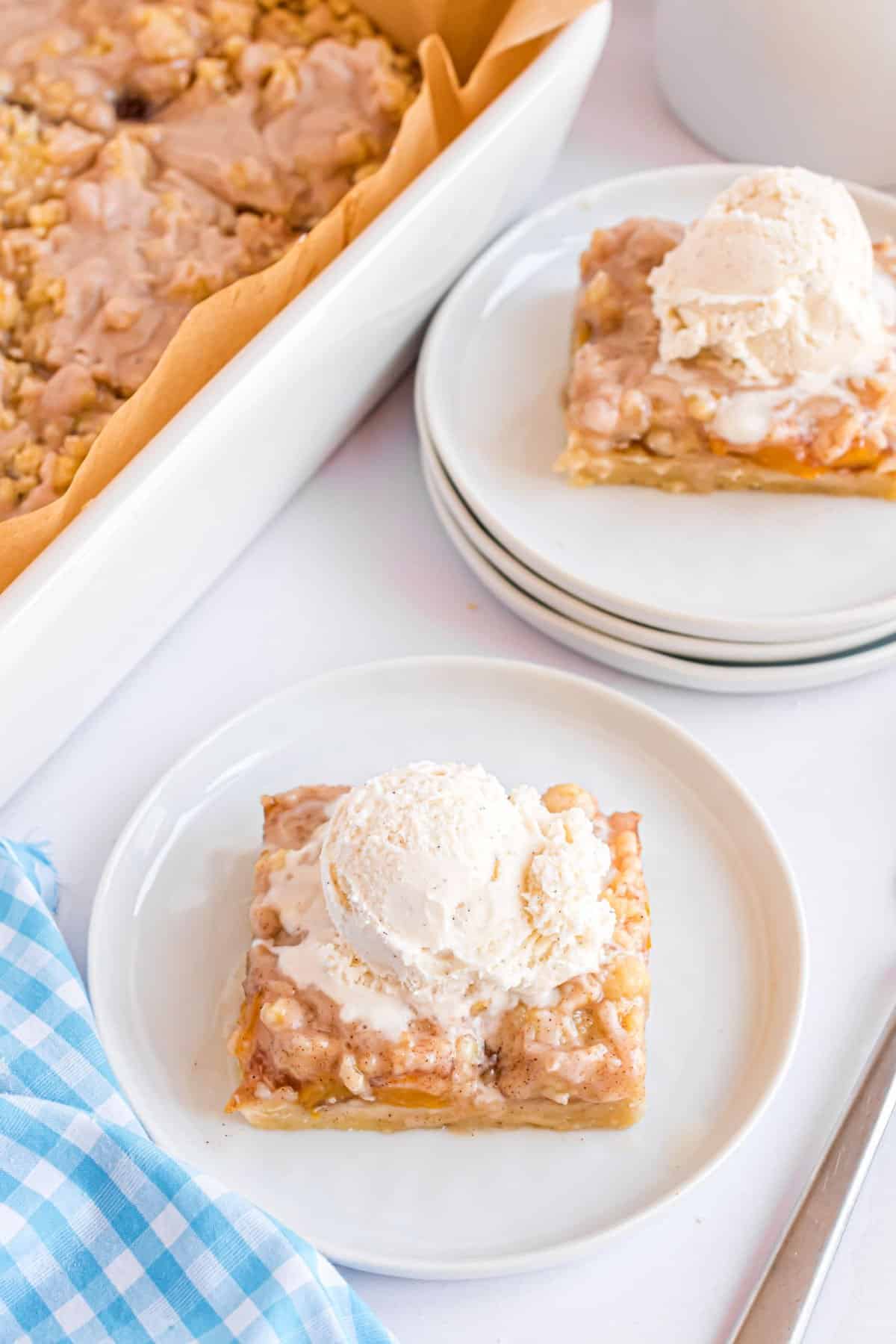 Peach pie bars topped with vanilla ice cream.