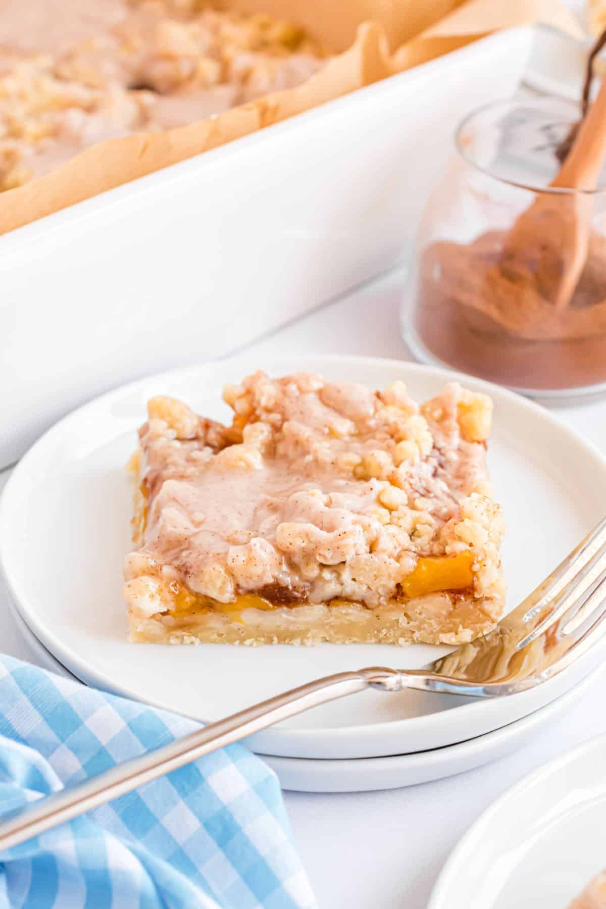 Peach pie bar served on a white plate with fork.