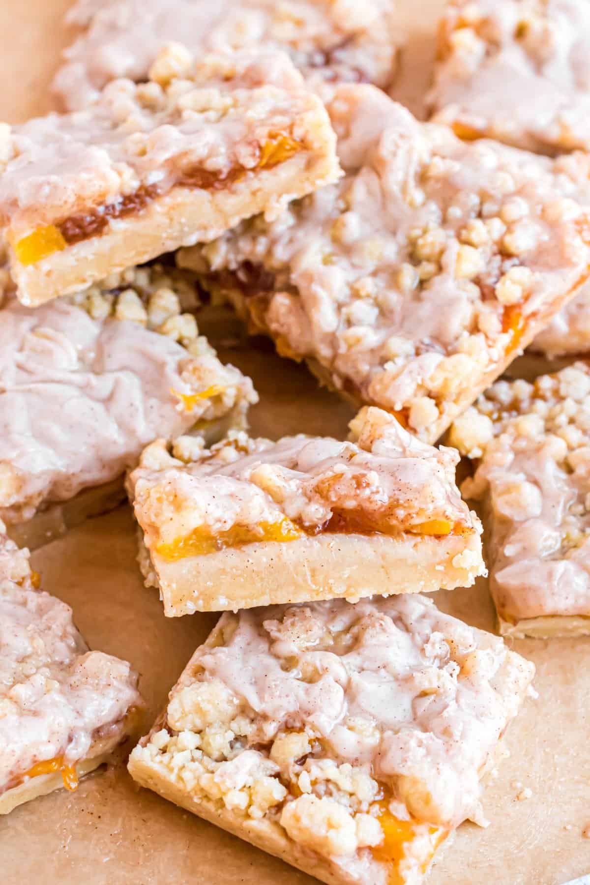 Peach pie bars cut into squares and stacked on parchment paper.