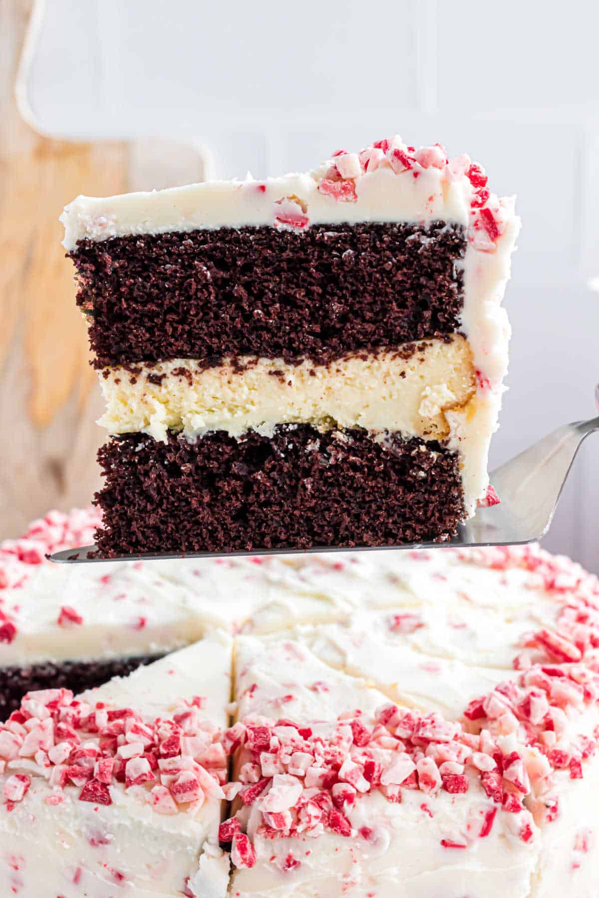 Slice of cake with chocolate layers surrpounding cheesecake and iced with peppermint frosting.