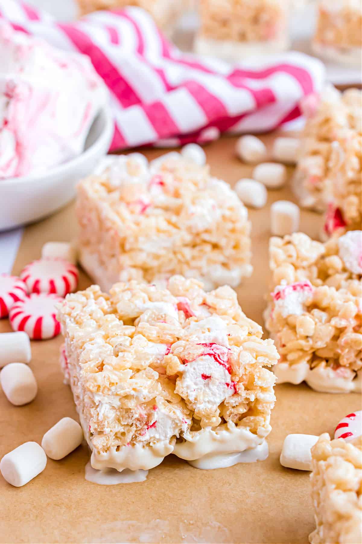 RIce krispie treats with peppermint marshmallows and white chocolate on parchment paper.