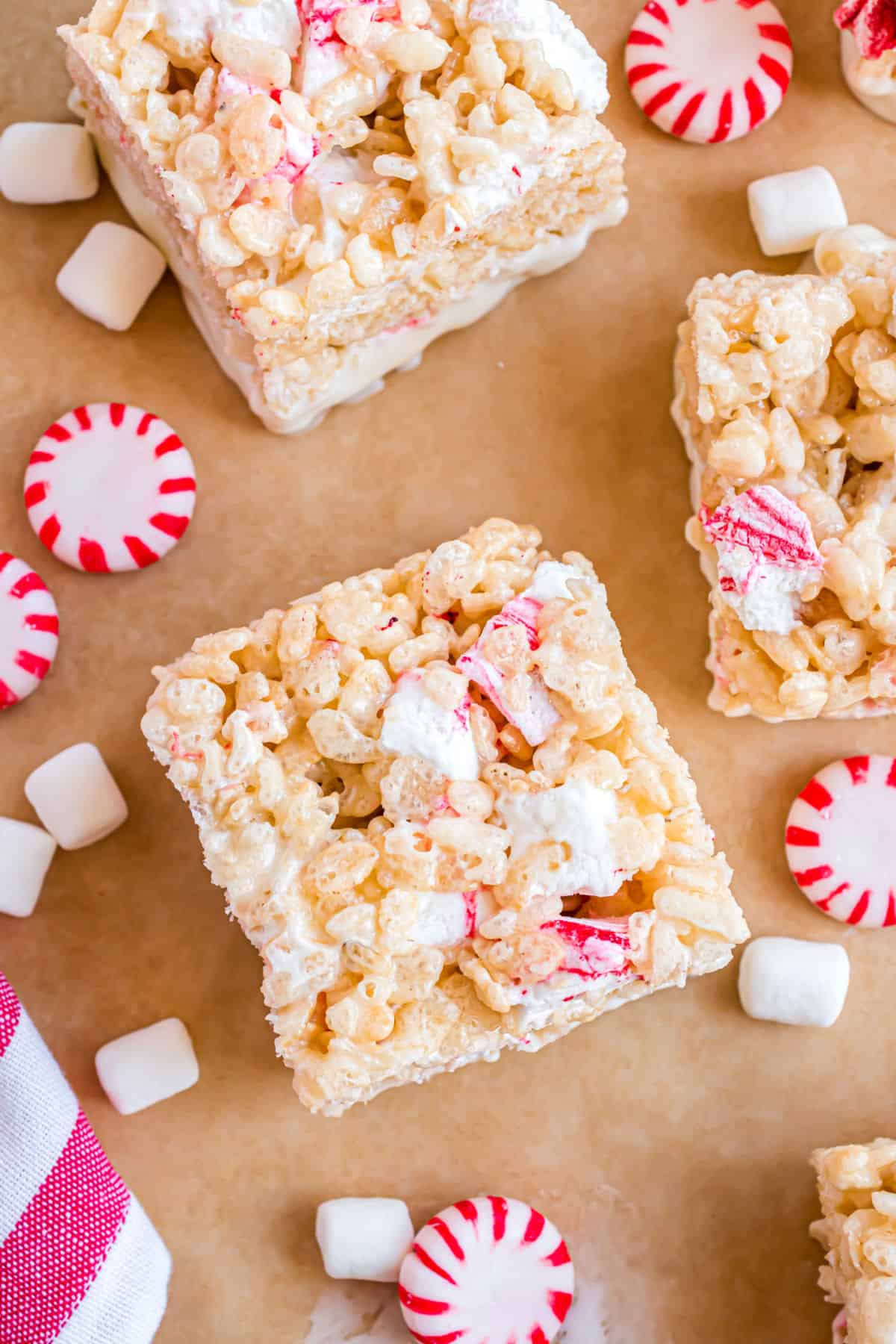 Squares of peppermint krispie treats on parchment paper.