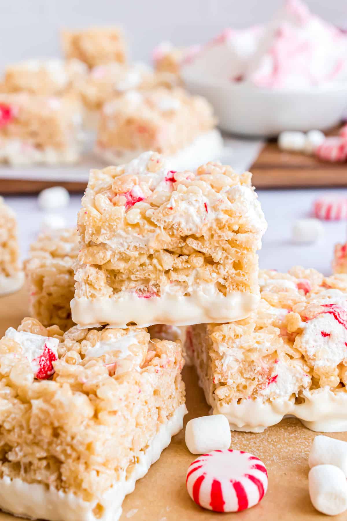Peppermint krispie treats stacked on parchment paper.