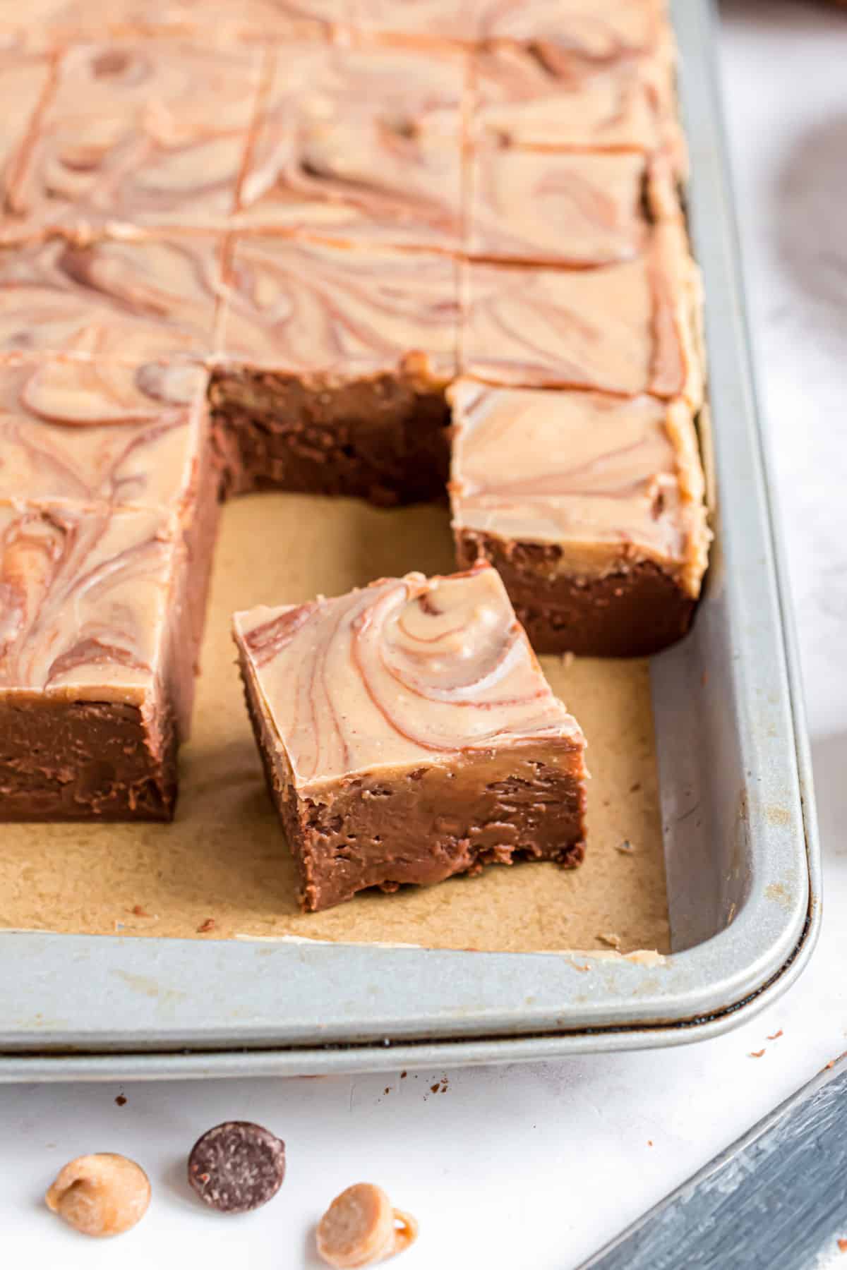 Chocolate peanut butter fudge in a large baking sheet with parchment paper.