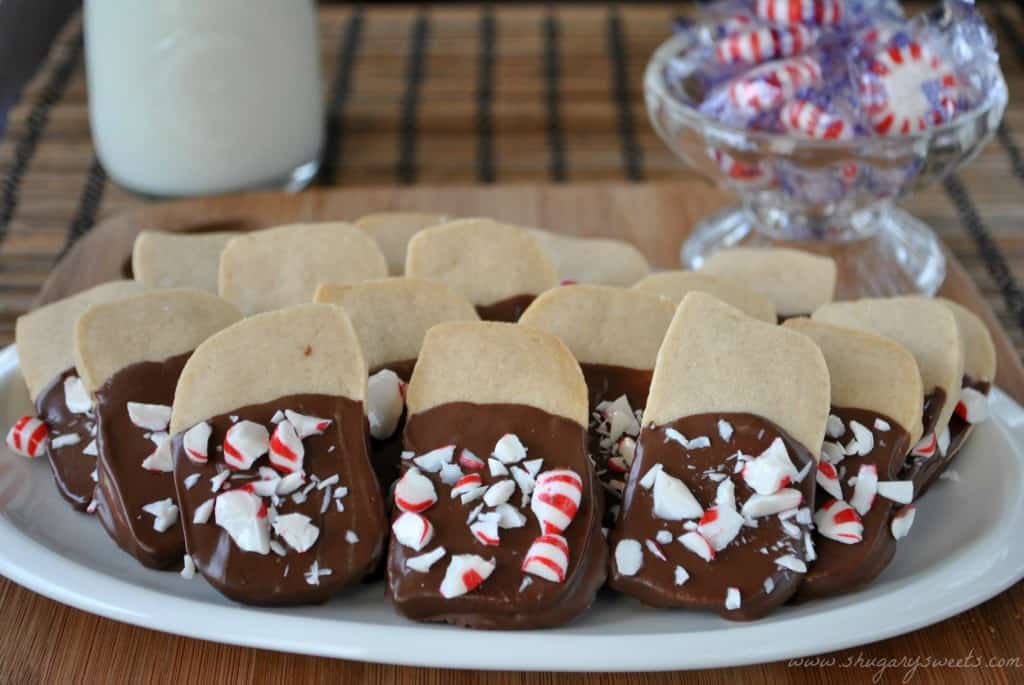 shortbread cookies dipped in chocolate and crushed peppermints with milk and peppermint candies in the background