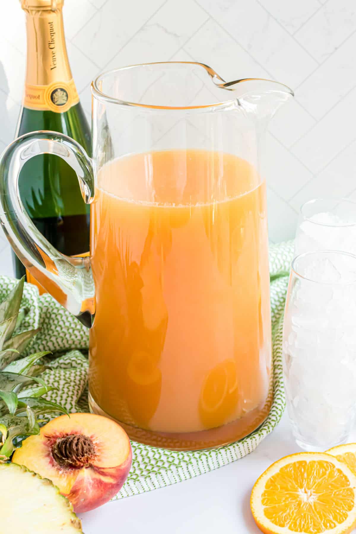 Large glass pitcher filled with a tropical cocktail.