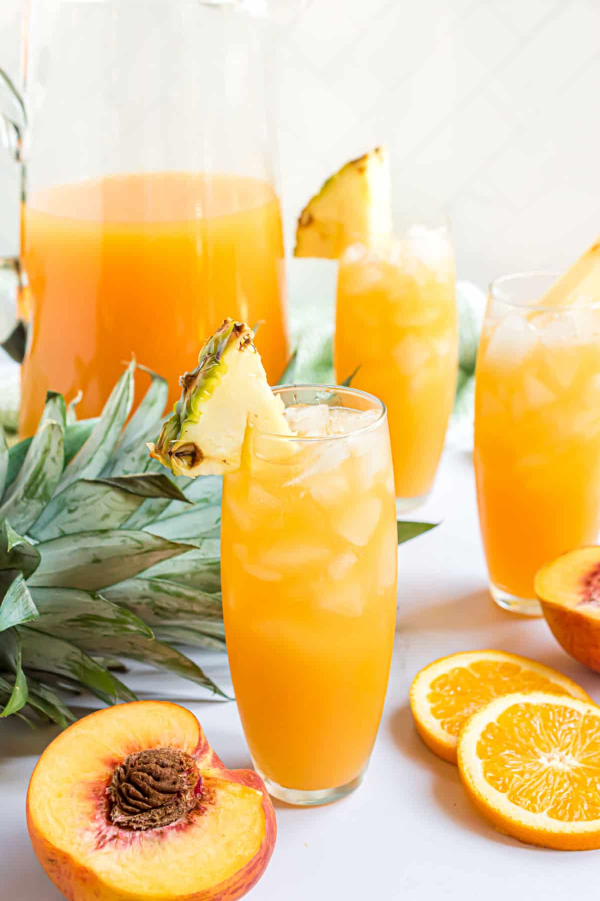 Tall glass of cocktail with a pineapple wedge for garnish.