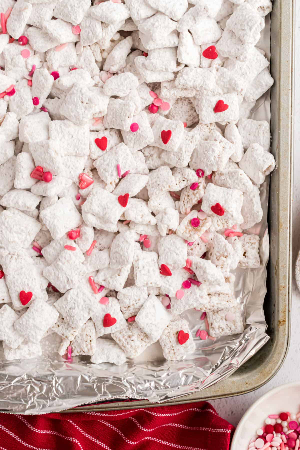Cherry puppy chow on foil lined cookie sheet.
