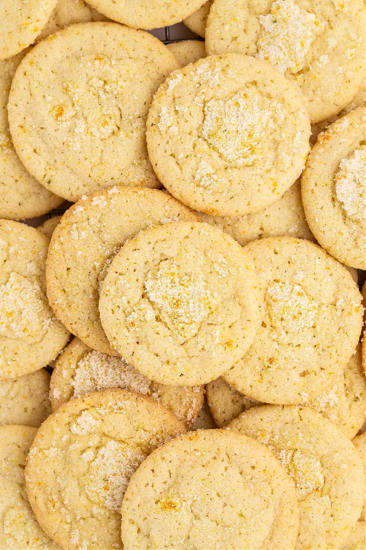 Orange, lemon, and lime cookies stacked on a cookie sheet after baking and cooling.