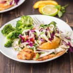 Grilled tilapia with tangy citrus slaw on a white plate.