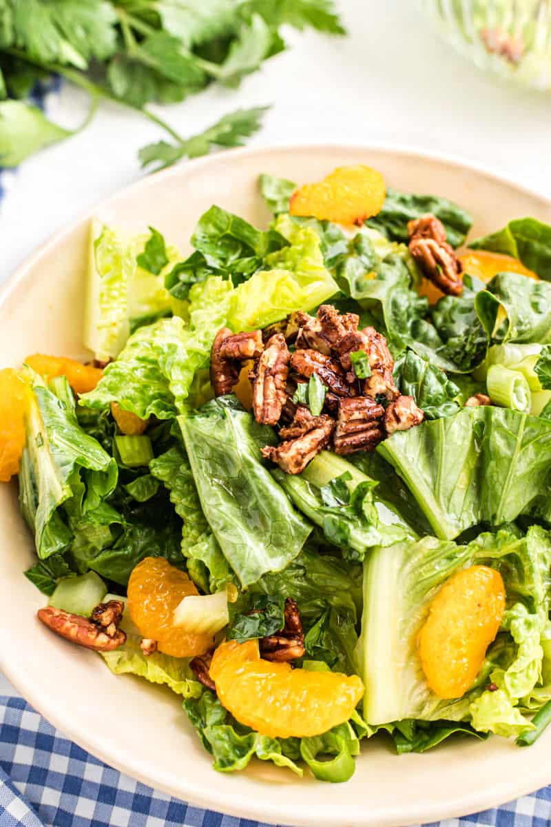 Mandarin salad with pecans in a white bowl.