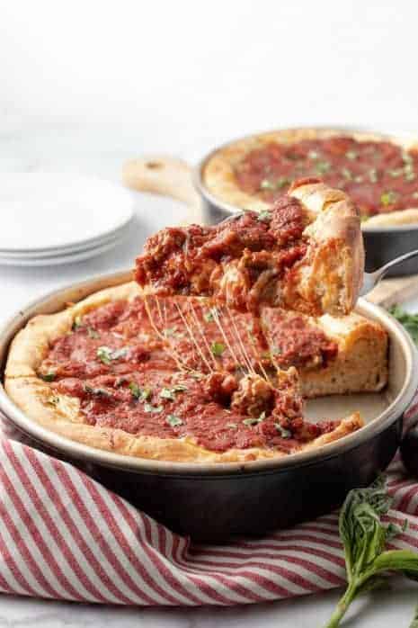 Slice of deep dish pizza being lifted out of a pan.