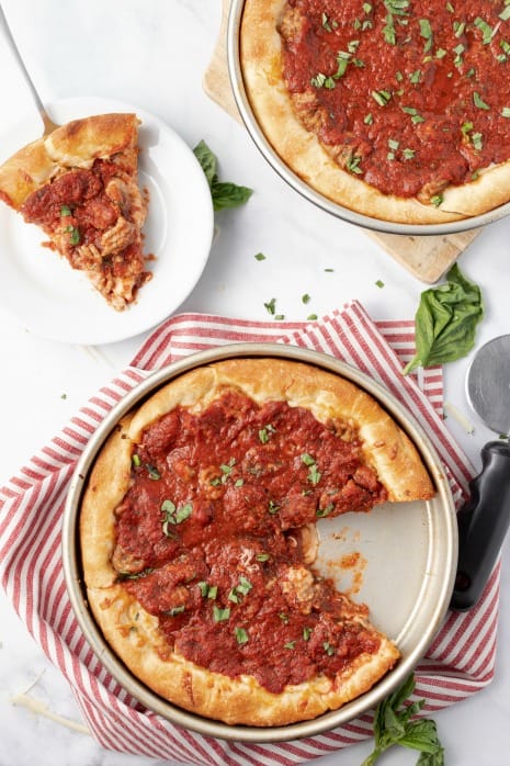 Deep dish pizzas with one slice on a plate.