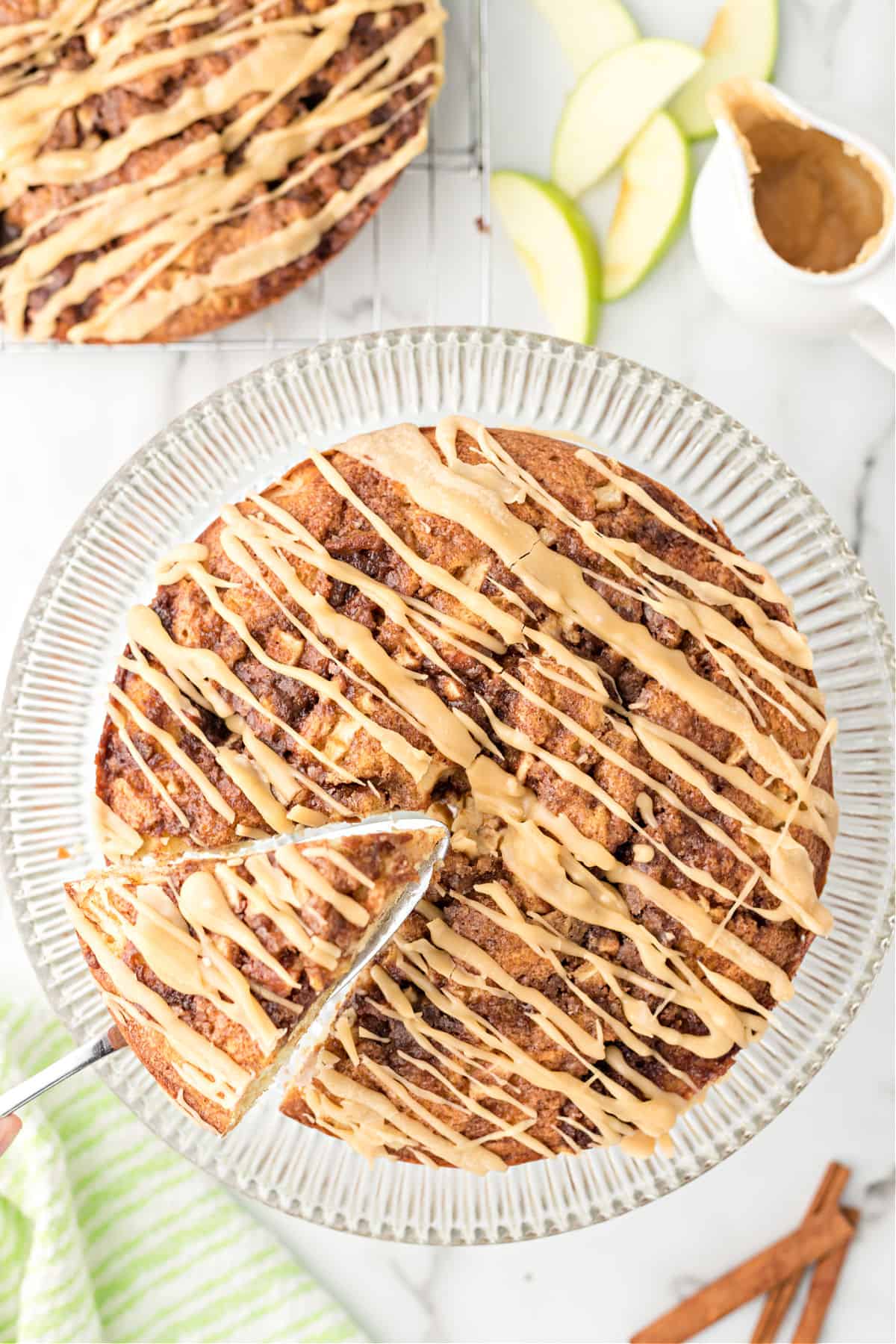 Caramel apple cinnamon rolls cakes with one slice being removed with a pie server.