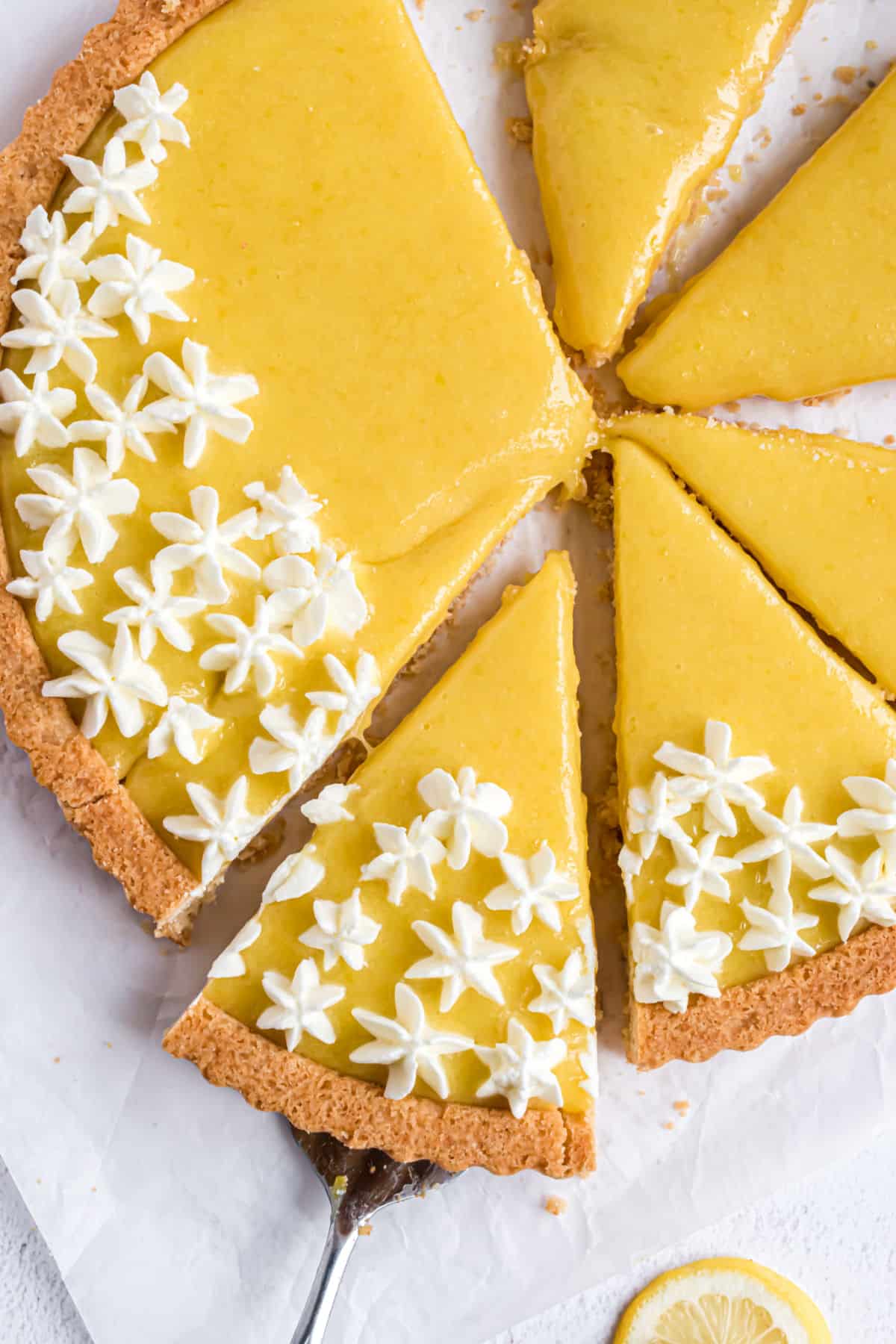 Lemon tart with whipped cream, sliced into triangles.