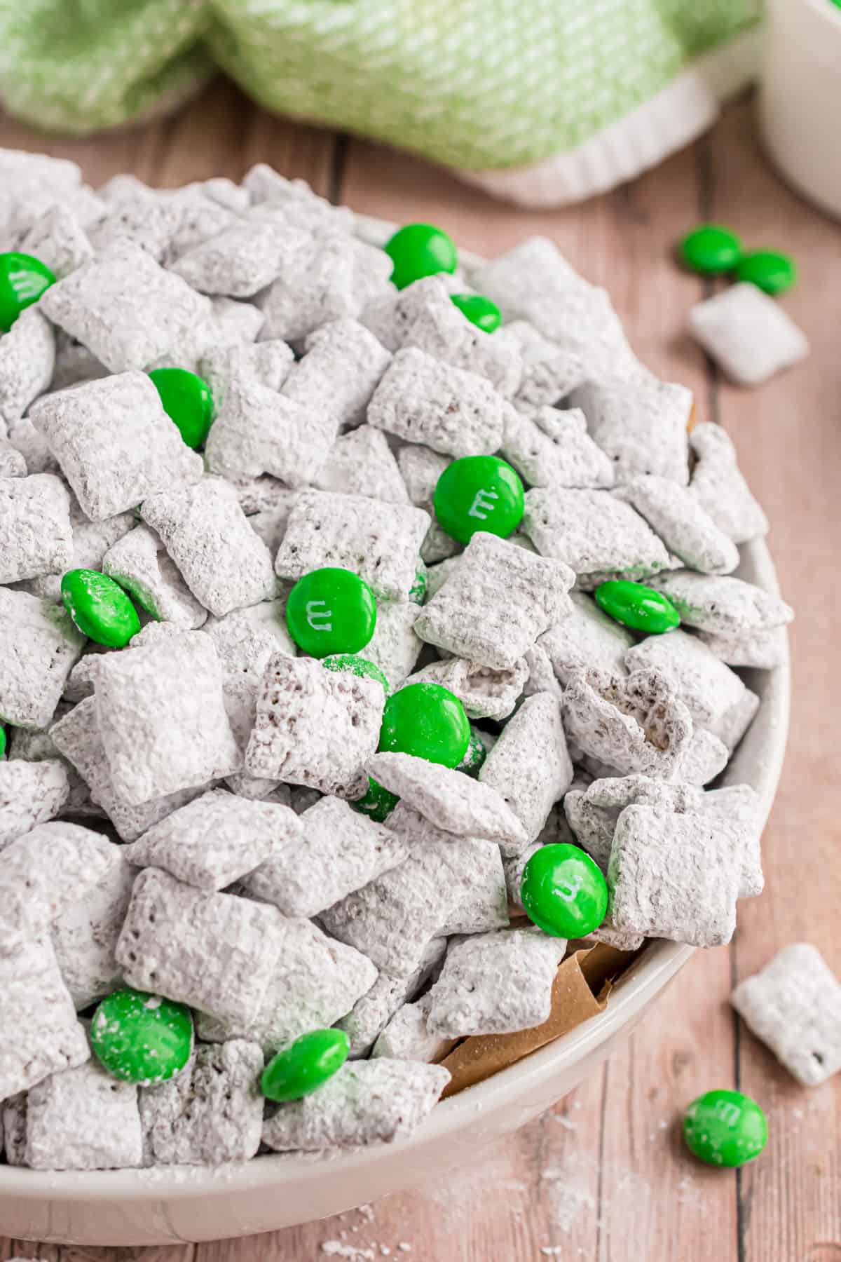 Thin mint puppy chow served in a white bowl with green min M&M candies.