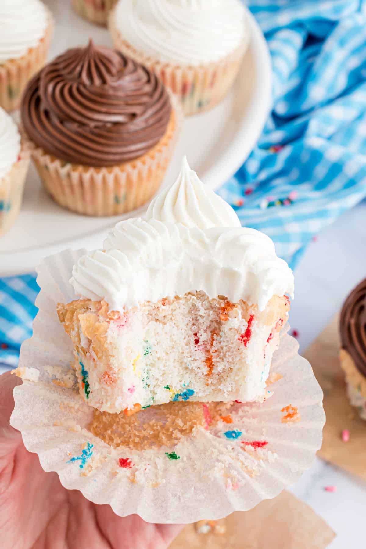 Funfetti cupcake with vanilla frosting and a bite taken out.