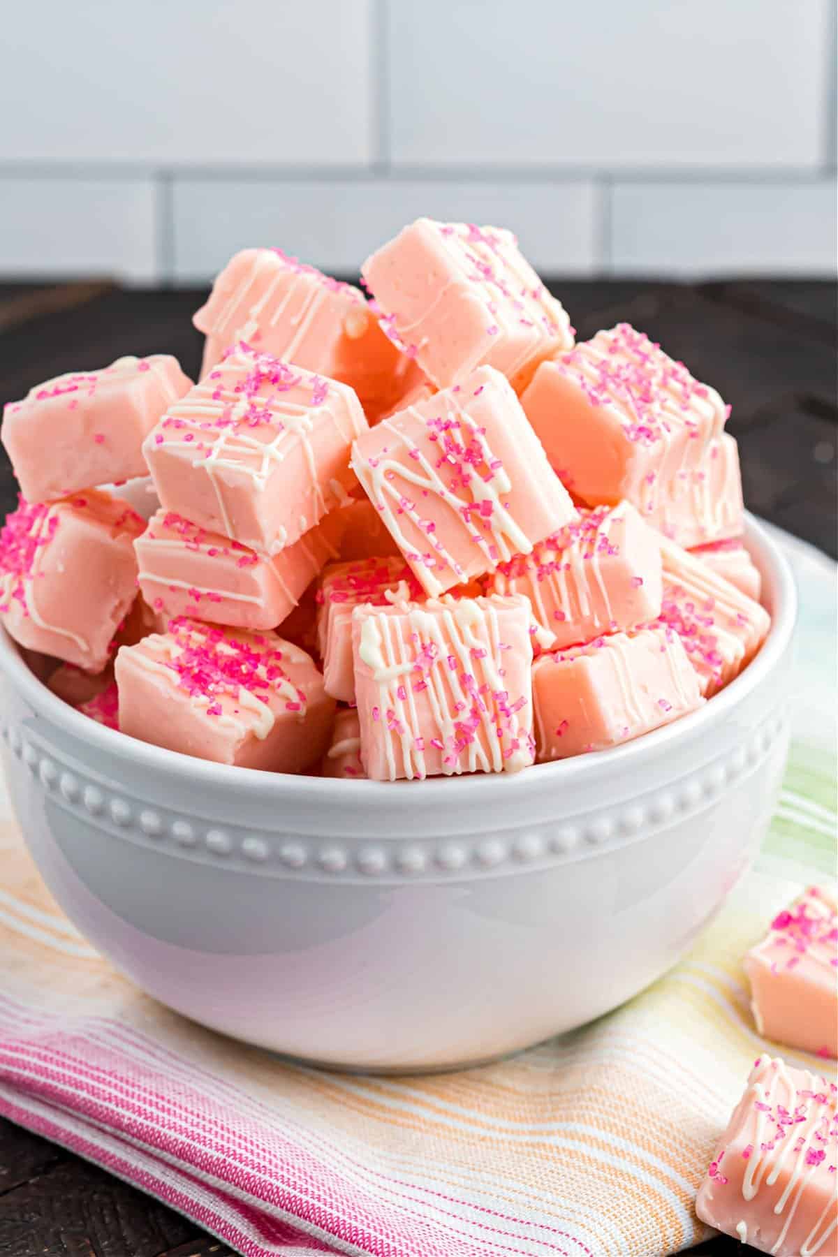 Pieces of pink lemonade fudge in a white serving bowl.