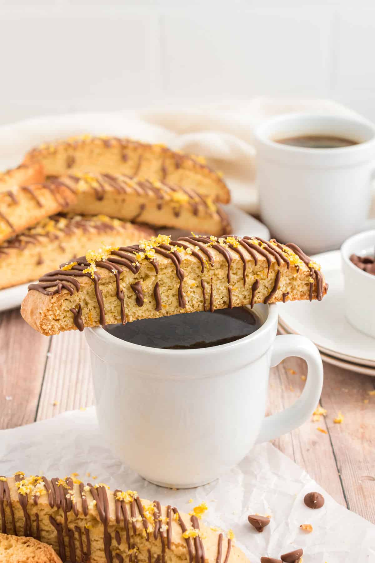 Piece of orange bisscotti on a cup of coffee.