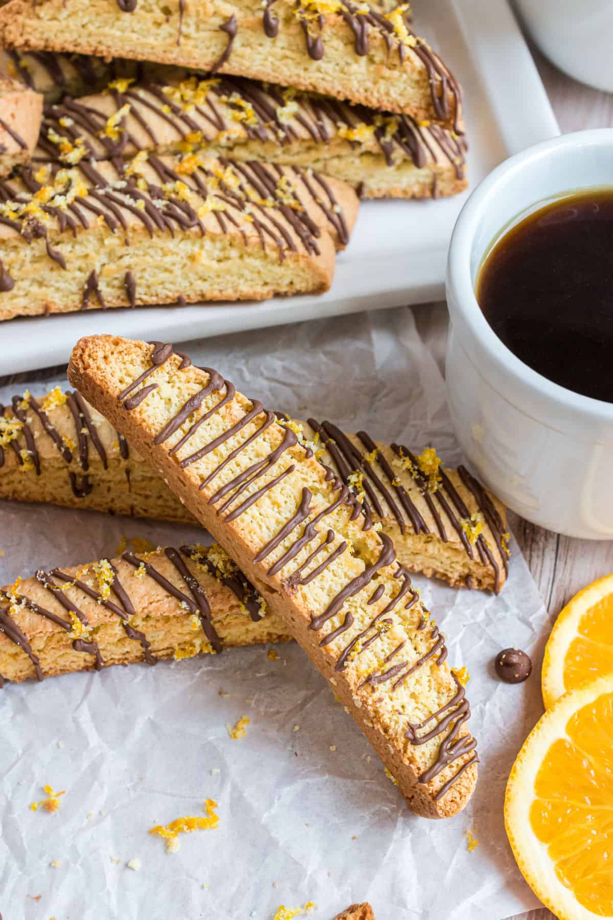 Stack of orange biscotti drizzled with chocolate.