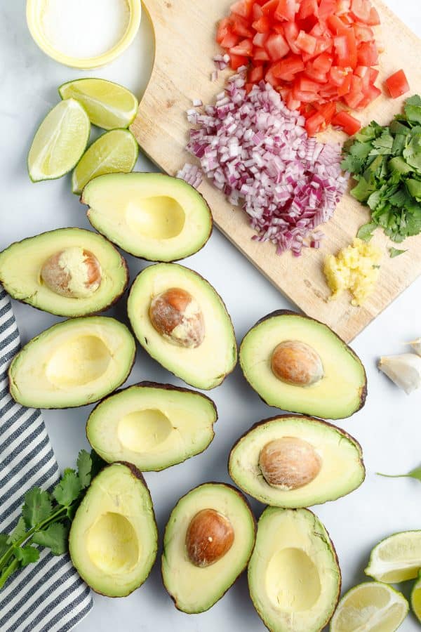 Ingredients for chunky guacamole: avocado, red onion, tomatoes, salt, lime, garlic, cilantro.