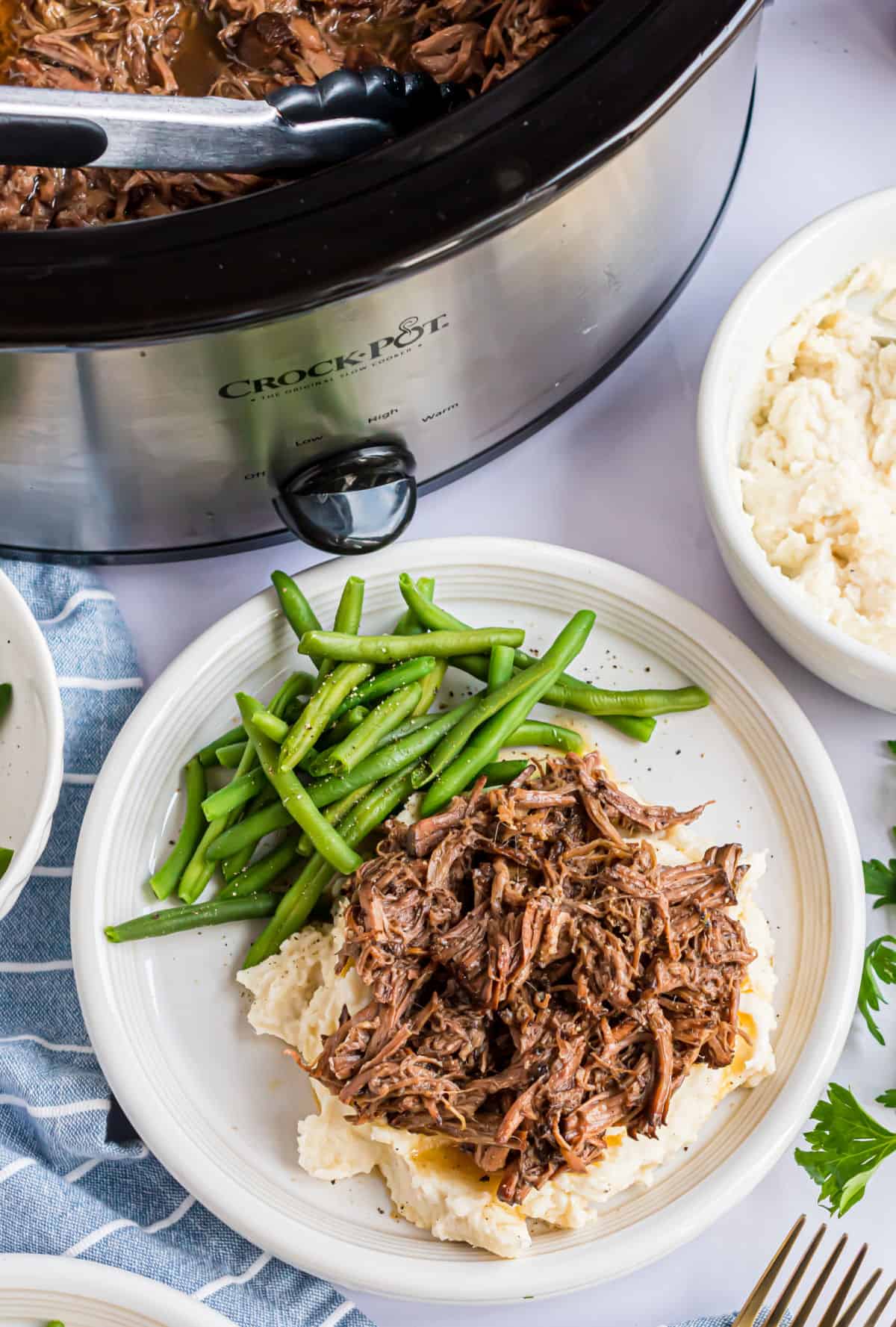 Shredded beef served over mashed potatoes and a side of green beans.