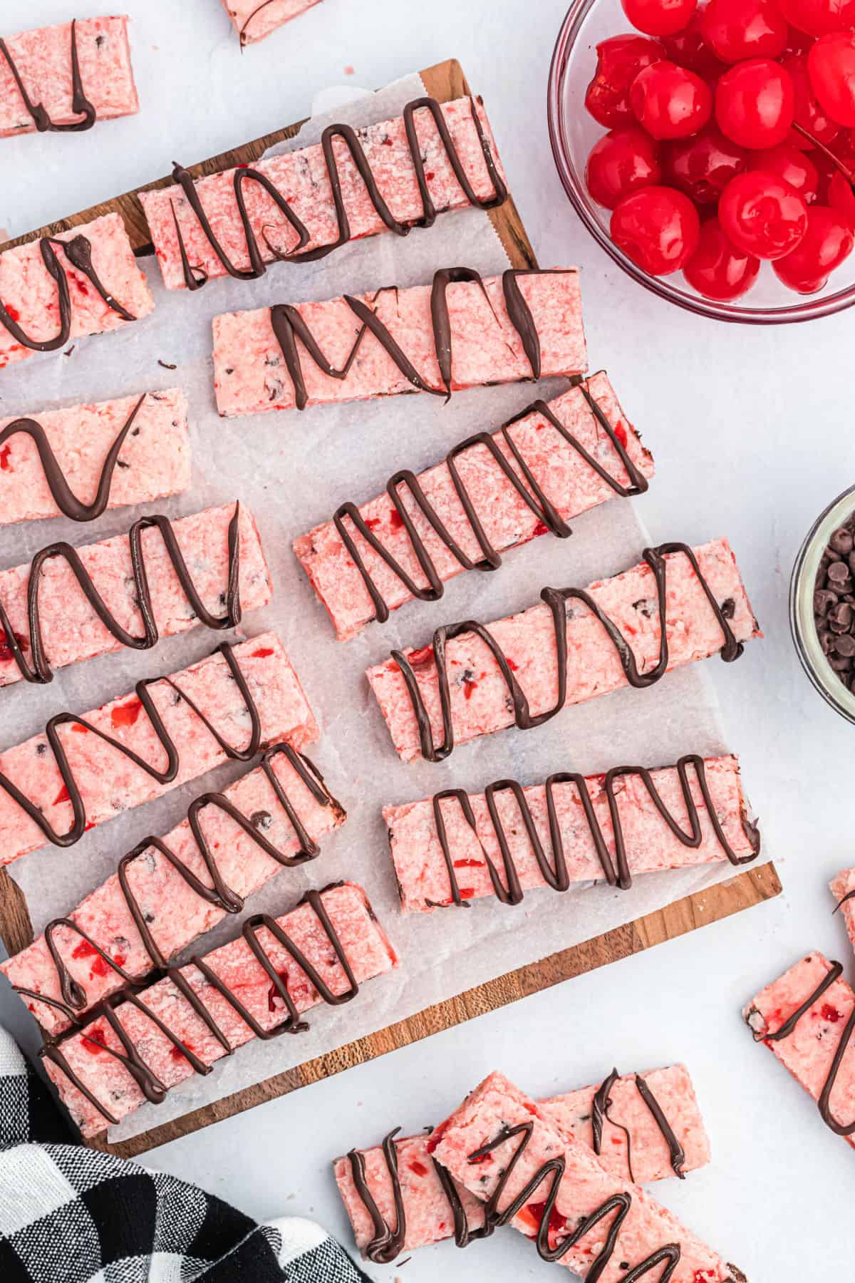 Cherry shortbread cookie bars on a parchment paper lined baking sheet.