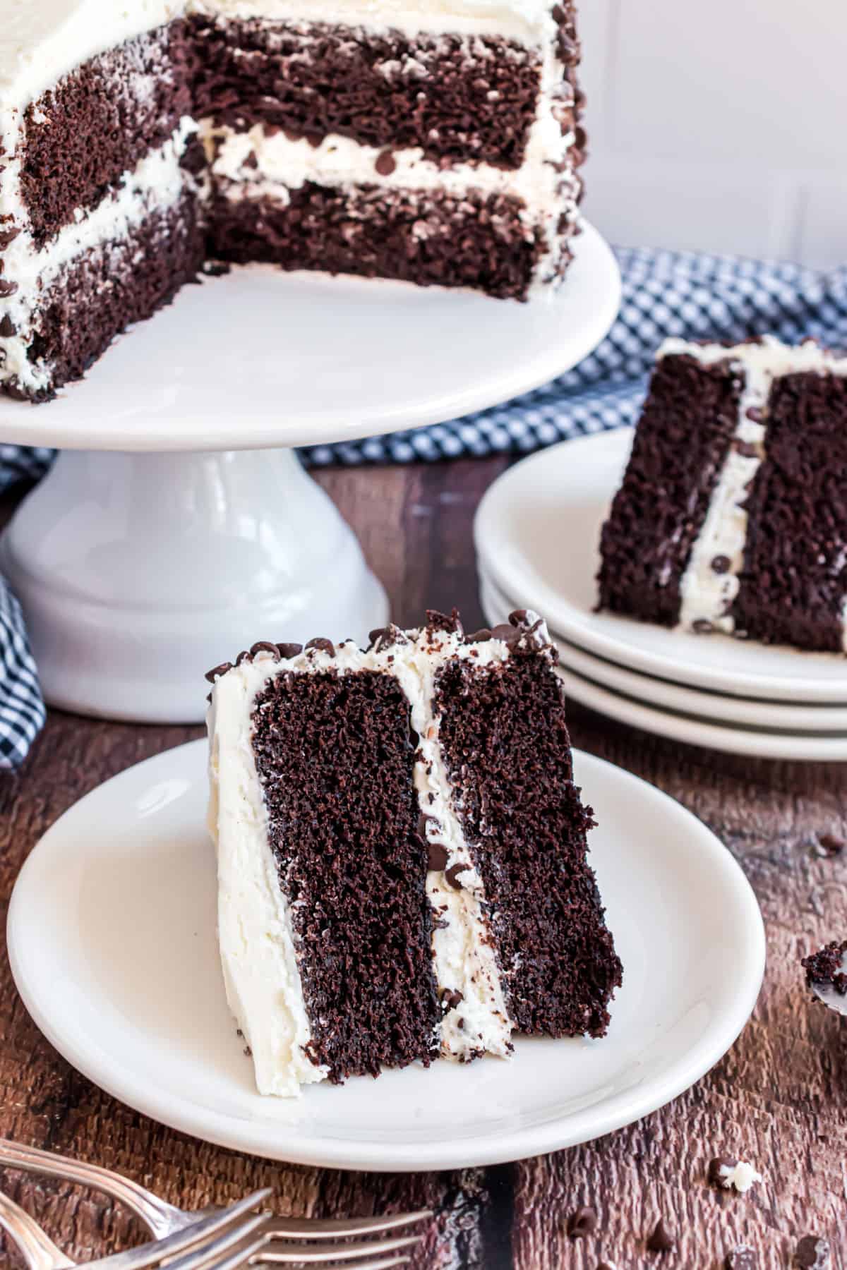 Dark chocolate cake slices on white plate and topped with vanilla frosting.