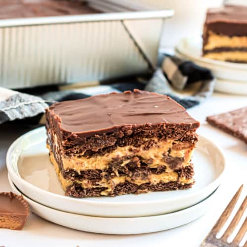Too hot to turn on the oven? Make this No Bake Peanut Butter Eclair Cake. Layers of chocolate graham crackers with pudding, peanut butter cups, and ganache.