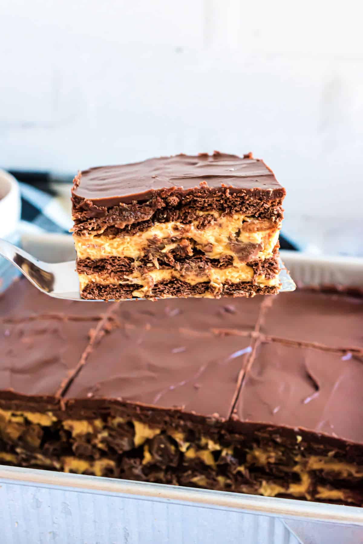 Eclair cake with peanut butter being lifted out of dish.