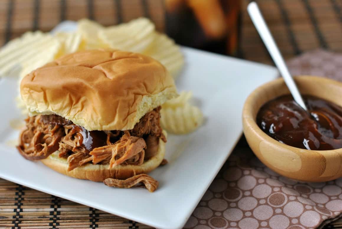 Pulled pork on a bun with a side of bbq sauce.