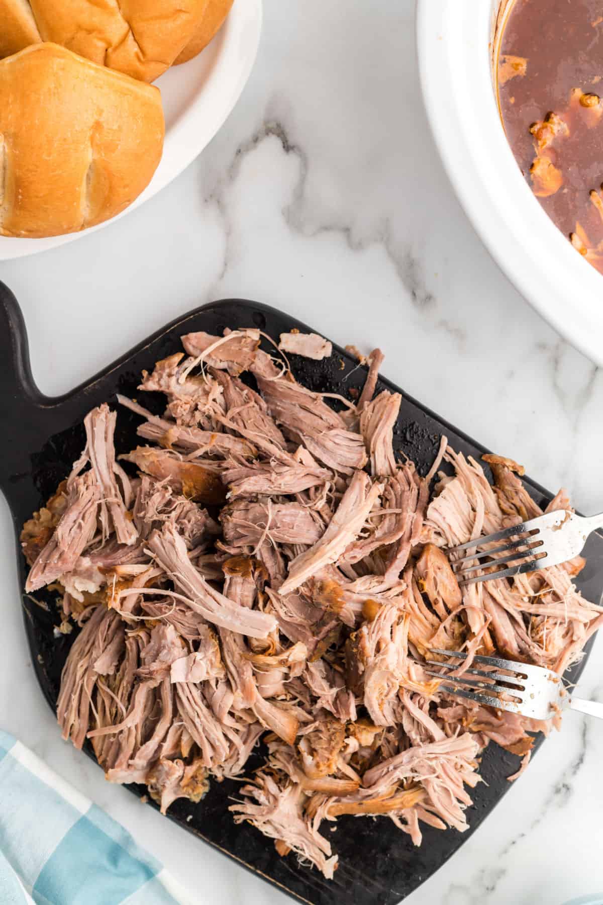 Shredded pulled pork on a cutting board.