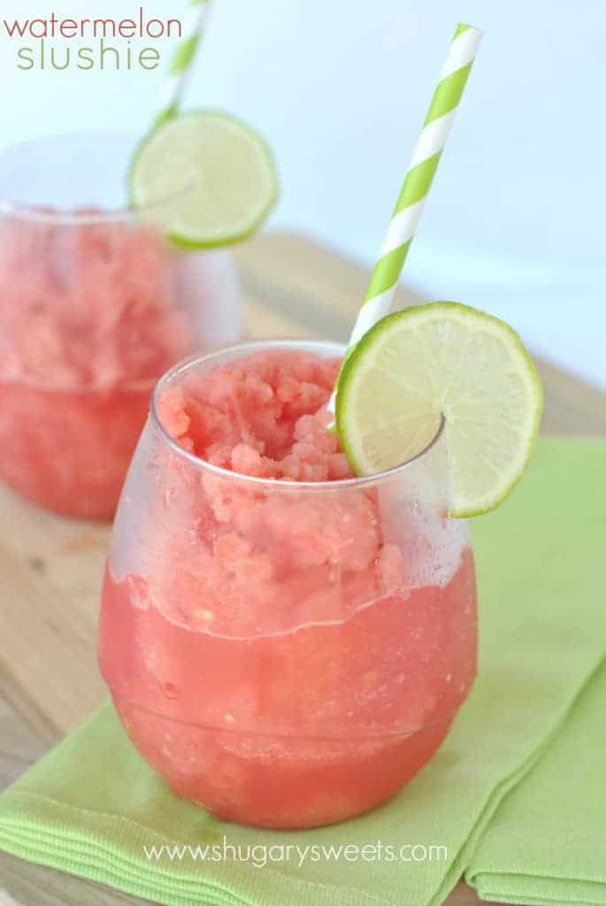 Watermelon Slushie: freeze watermelon cubes and blend with lime juice for a refreshing slushie drink! Watermelon slushie in two stemless wine glasses with lime garnish.