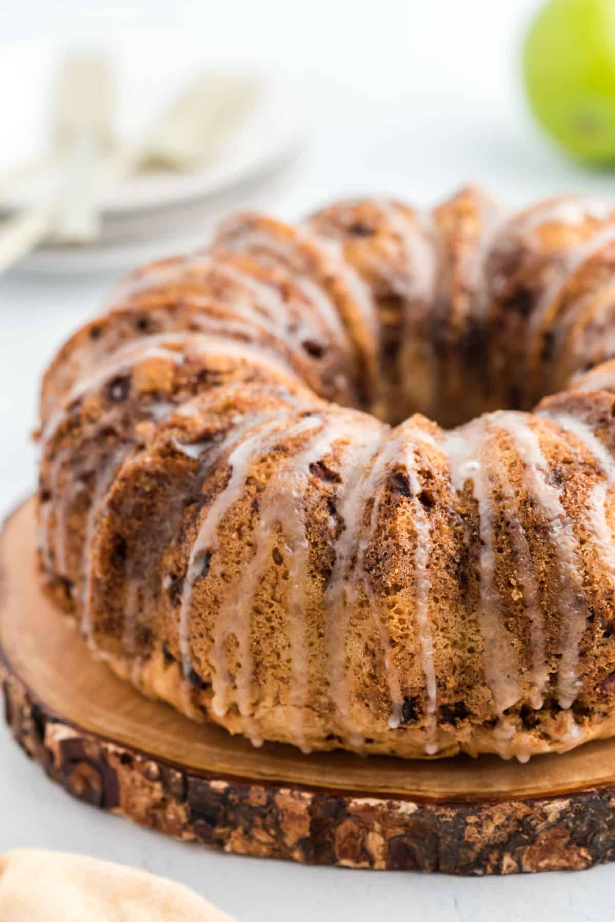 Apple bundt cake on wooden serving plate with a glaze.