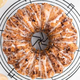 Apple bundt cake drizzled with honey icing on a wire cooling rack.