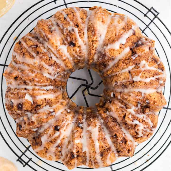 Apple bundt cake drizzled with honey icing on a wire cooling rack.