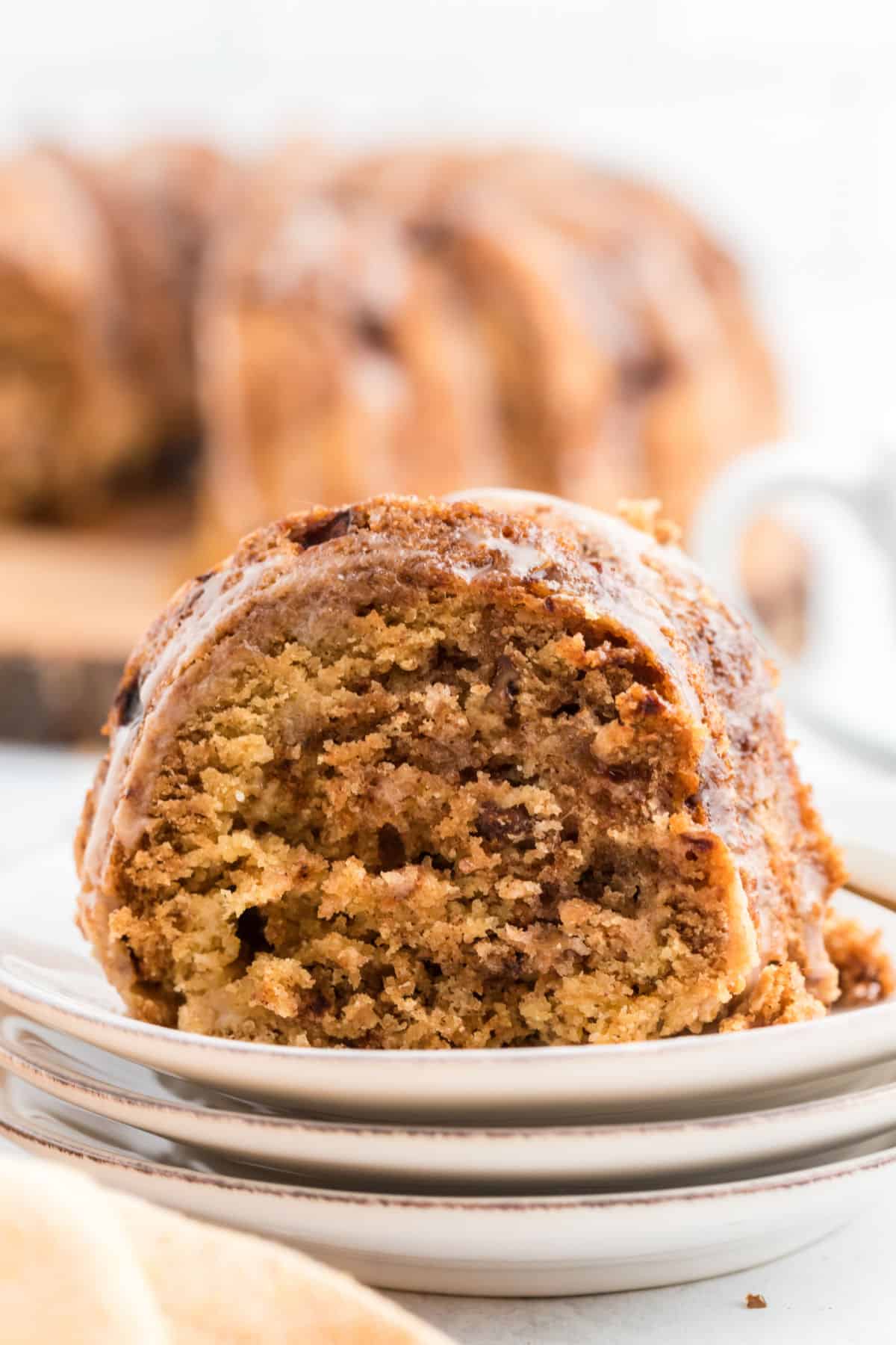 Apple cake slice on a stack of white plates.