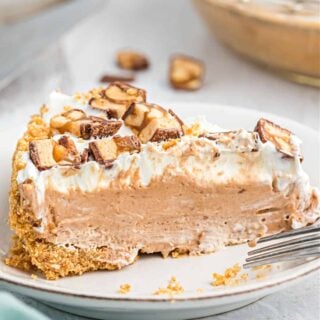 Slice of frozen snickers pie on a white dessert plate.