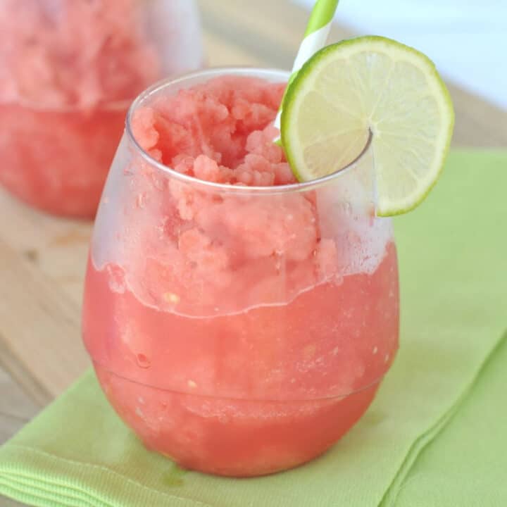 Watermelon slush in stemless wine glass with lime slice garnish.