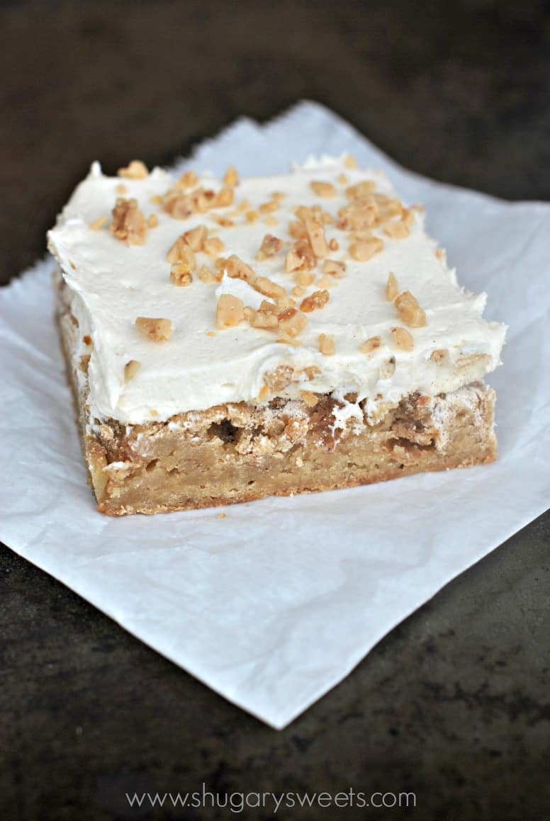 Apple blondie on a piece of parchment paper with frosting and toffee.