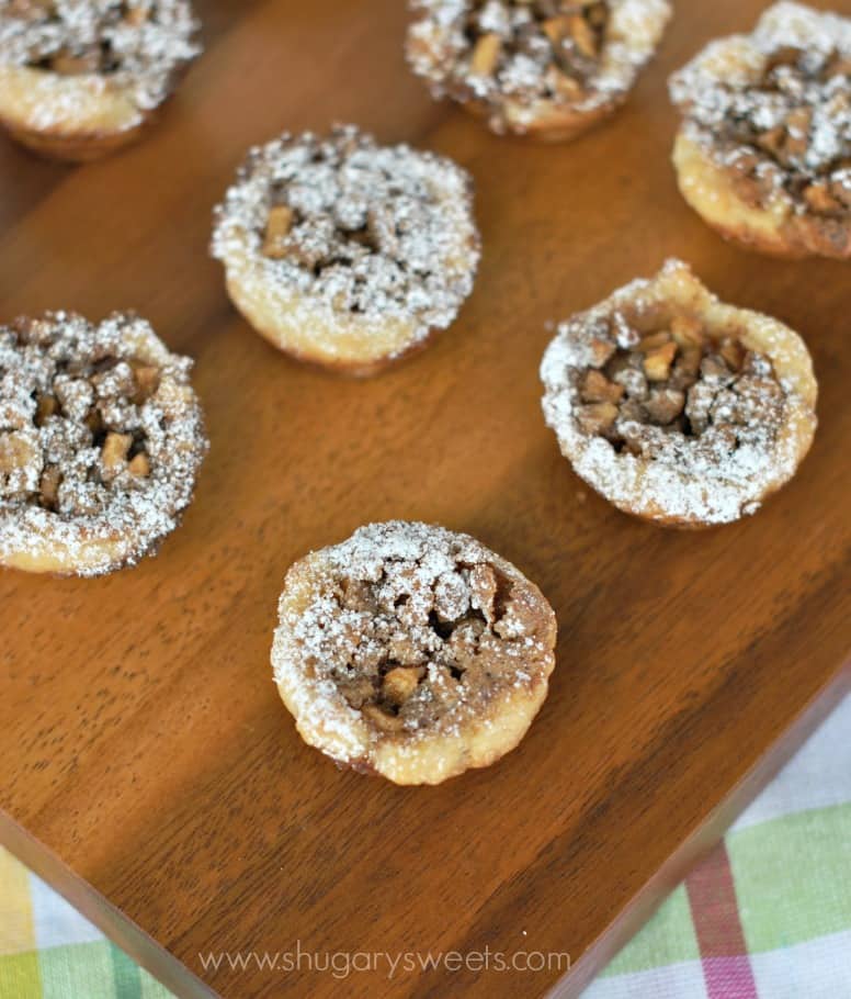 Apple pecan cookies on a wooden cutting board with powdered sugar.