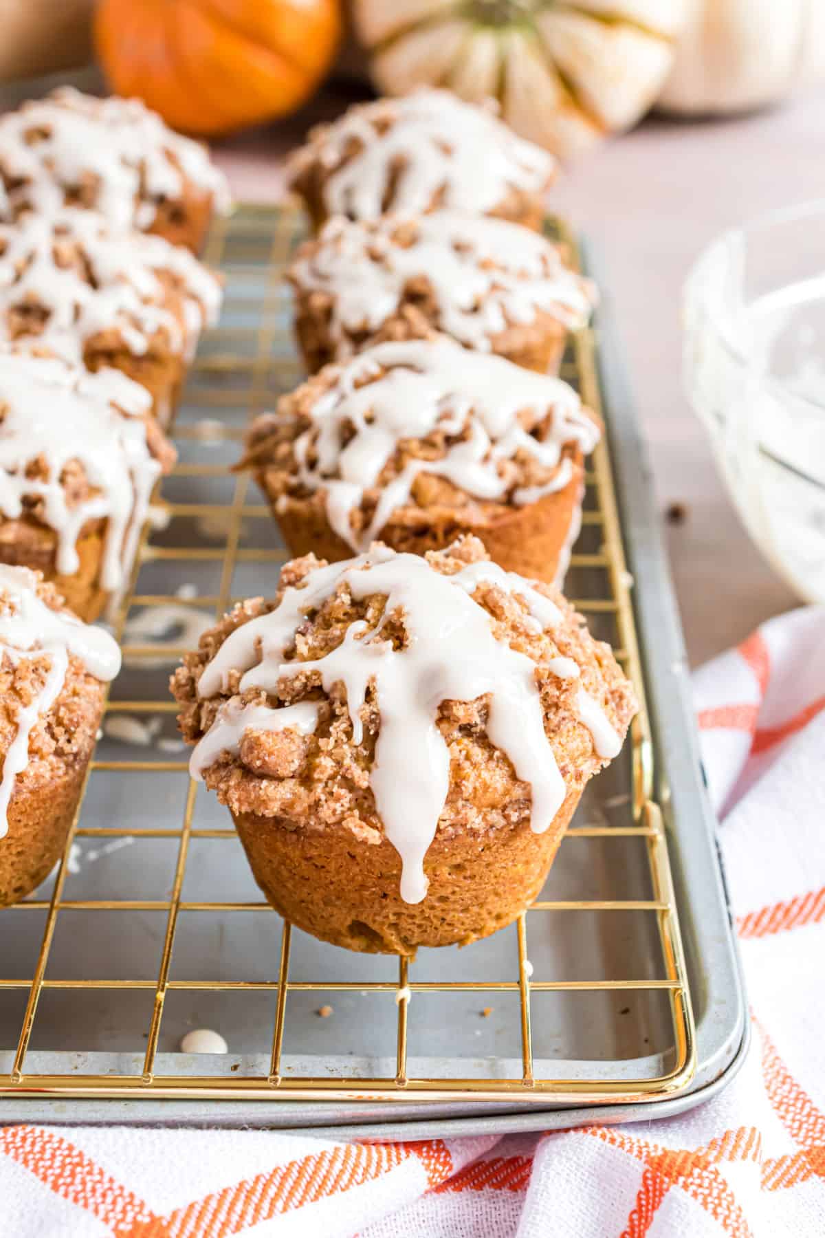 Pumpkin muffins on wire rack with vanilla glaze.