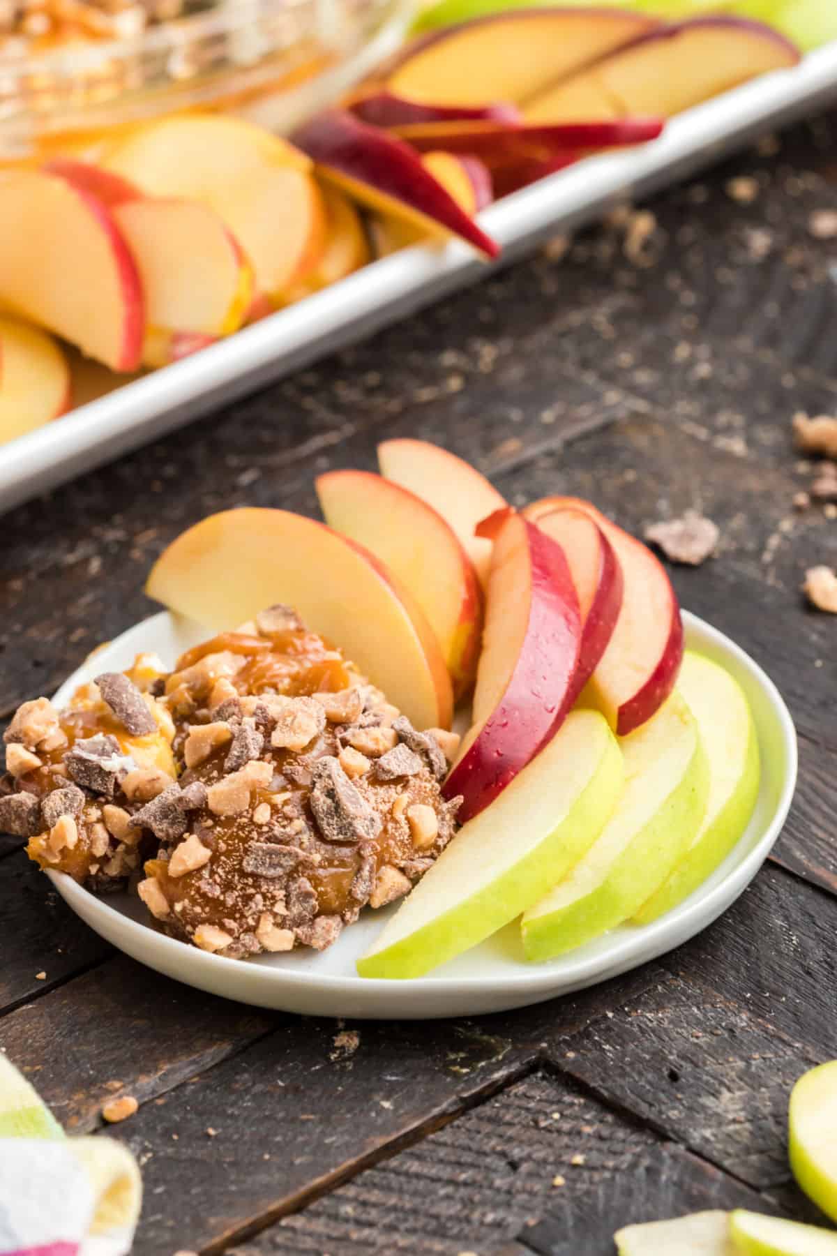 Caramel apple dip on a small white plate with apple slices.