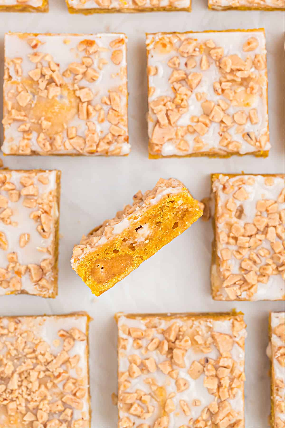 Pumpkin blondies with icing on parchment paper.